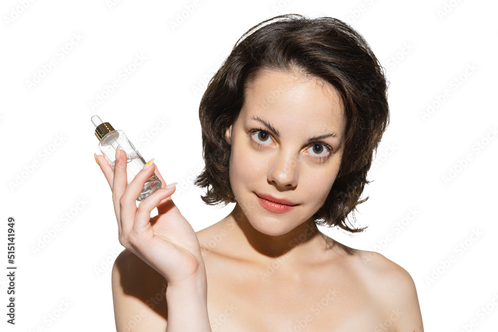 Half-length portrait of charming young girl without makeup holding moisturizing lotion bottle isolated over white studio background. Anti-aging cosmetics Half-length portrait of charming young girl without makeup holding moisturizing lotion bottle isolated over white studio background. Anti-aging cosmetics