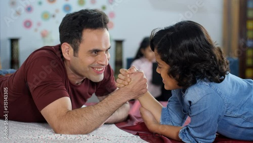 A young boy playing arm-wrestling with his father - physical strength happy parenting a competitive match. A happy Indian family together at home - family bonding leisure time an Indian house... photo