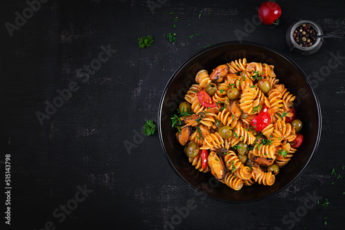 Classic italian pasta fusilli marinara with mussels, green olives and capers on dark table. Fusilli pasta with sauce marinara. Top view, overhead