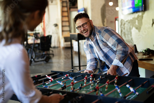 Colleagues having fun at work. Businessman and businesswoman playing table soccer