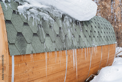 Icicles hang on the roof of the house. Spring melts snow, ice melts from the roof of the house. Roofing roof tiles on the roof. photo