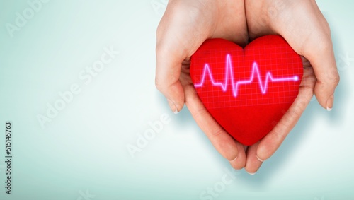 World Hypertension Day. Adult holds a red heart with a heartbeat chart, a symbol of high blood pressure. photo
