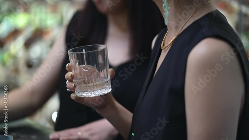 closeup shot of Asian female hands holding whisky glasses chatting at a bar