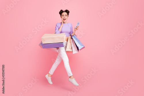 Full length body size view of beautiful trendy cheery girl jumping using device web offer isolated over pink pastel color background