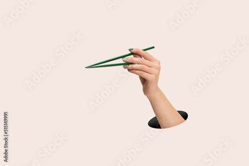 Stampa su tela Female hand holding green chopsticks on clean pink background
