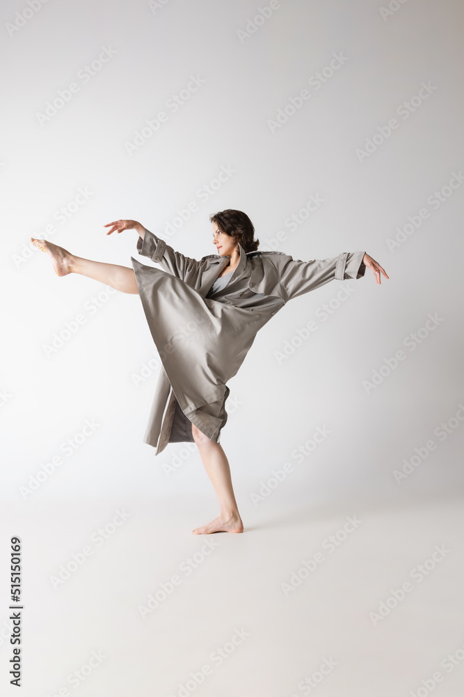 Dancing young thin woman in lingerie and coat in motion isolated on grey background. Art, beauty, action, flexibility, inspiration concept. Dancing young thin woman in lingerie and coat in motion isolated on grey background. Art, beauty, action, flexibility, inspiration concept.