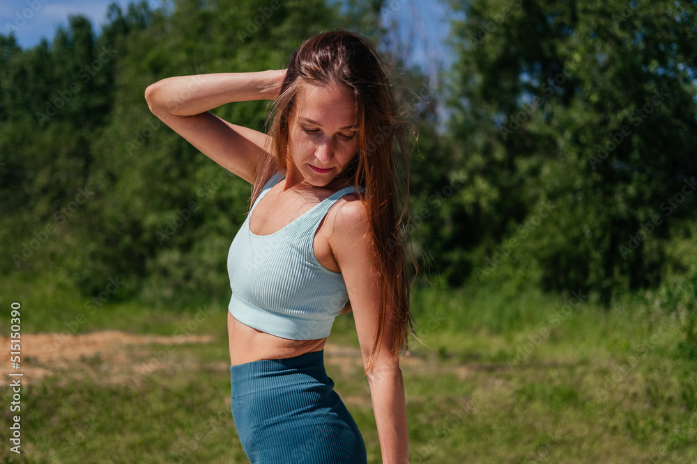 Middle aged woman in sportswear standing outdoors. Fitness woman looking down Middle aged woman in sportswear standing outdoors. Fitness woman looking down