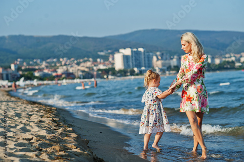 Mother and beautiful daughter having fun on the beach. Portrait of happy woman with cute little girl on vacation. © AS Photo Family