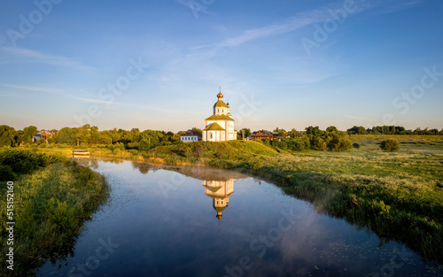 Small christian church on the river on a sunrise (aerial drone photo). Suzdal, Russia