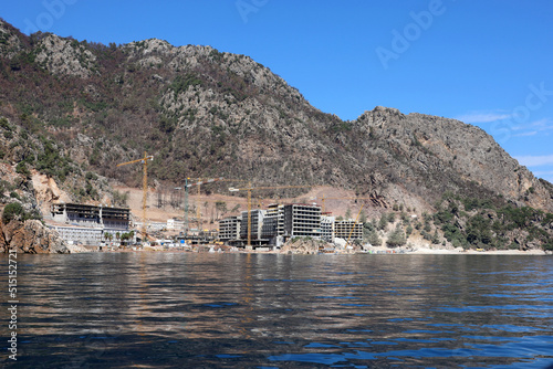 Construction of hotel buildings on a mountain beach in Mediterranean sea. Development of summer resort in Turkey © Oleg