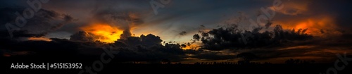 Panorama Large photo of Landscape sunset with dark clouds.Tree silhouetted against a setting sun.Dark tree on open field dramatic sunrise and Orange sky.Majestic Landscape Dark Clouds sunset Sky.