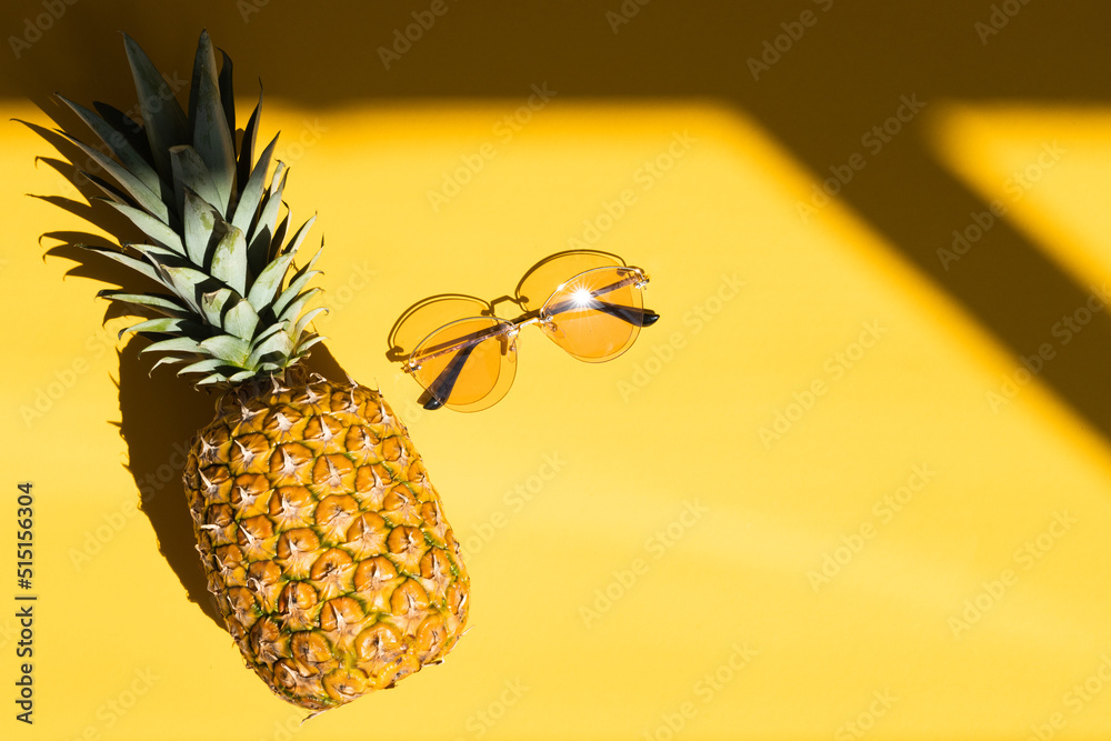 Hipster pineapple and coconuts with sunglasses against a yellow background
