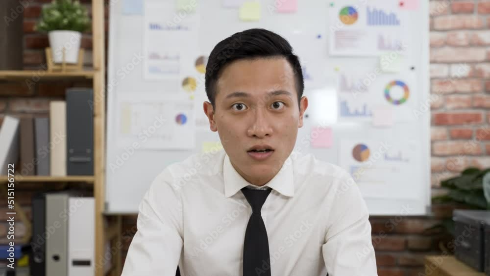 shoulder shot asian male manager looking at webcam is talking with hand gestures while expressing ideas to client during a video conference call in the office.