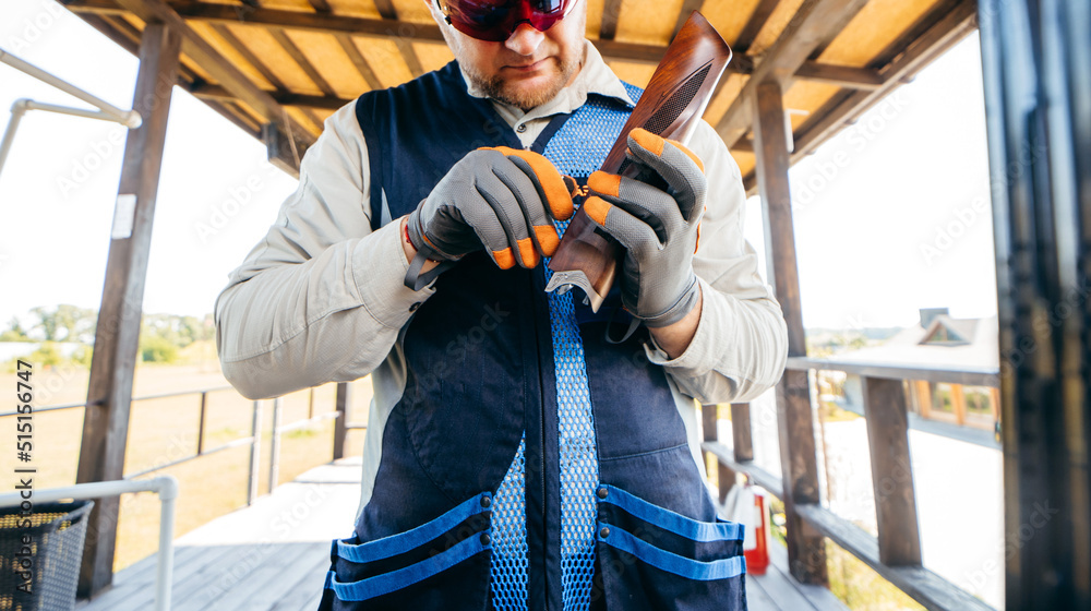 Αυτοκόλλητο Adult shooter in sunglasses and gloves adjusts his gun with a hexagon before a c