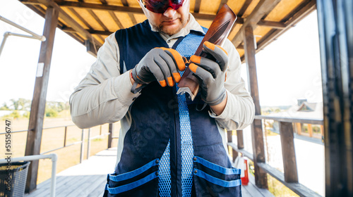 Photos Adult shooter in sunglasses and gloves adjusts his gun with a hexagon before a c