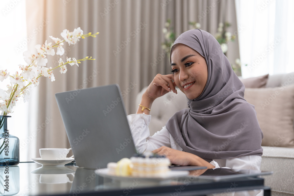 Muslim young women wear hijab using computer laptop at home morning. Concept business small and shop online Muslim young women wear hijab using computer laptop at home morning. Concept business small and shop online