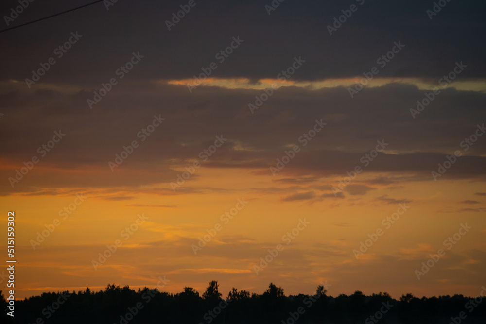 dramatic red sunset colors in the sky above trees and fields. summer sunset in latvia dramatic red sunset colors in the sky above trees and fields. summer sunset in latvia