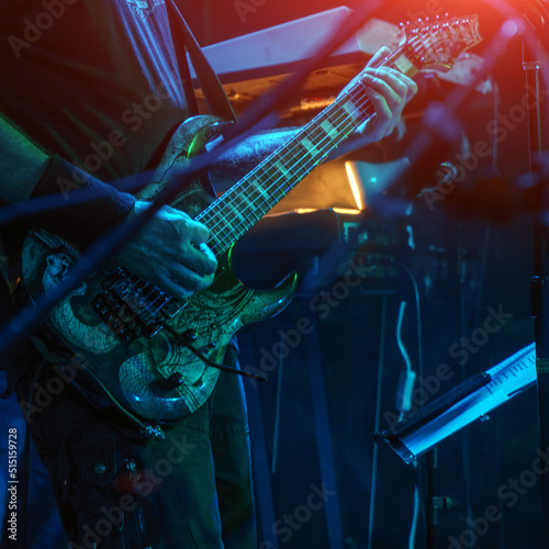 The guitarist plays the guitar in the spotlight. Hands of a Guitar player playing the guitar. Selective focus. Soft focus
