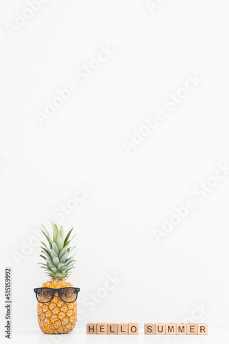Fresh pineapple wearing sunglasses on color background. Hello summer