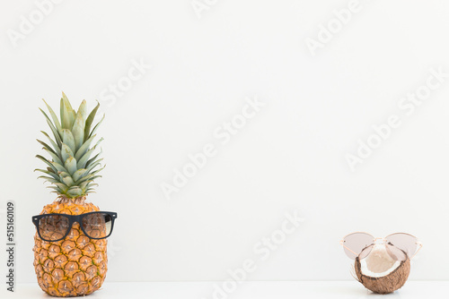 Fresh pineapple and coconut with sunglasses on color background. Hello summer