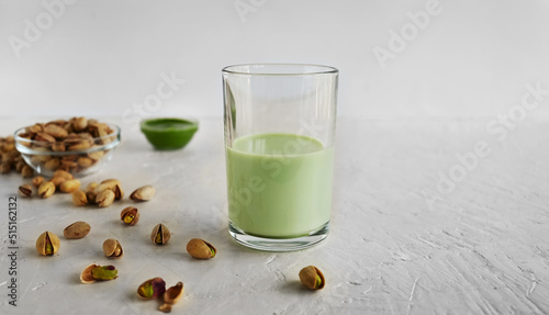 Pistachio milk in the glass and pistachio paste  on the white background. This milk is a great source of antioxidants, phytosterols, and heart healthy fats