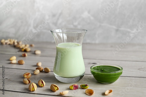 Pistachio milk in the glass and pistachio paste  on the wooden background. This milk is a great source of antioxidants, phytosterols, and heart healthy fats