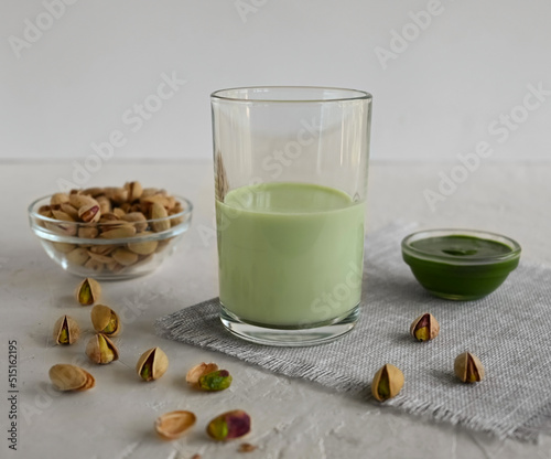 Pistachio milk in a glass, pistachio paste, and pistachio on a linen napkin. This milk is a great source of antioxidants, phytosterols, and heart healthy fats