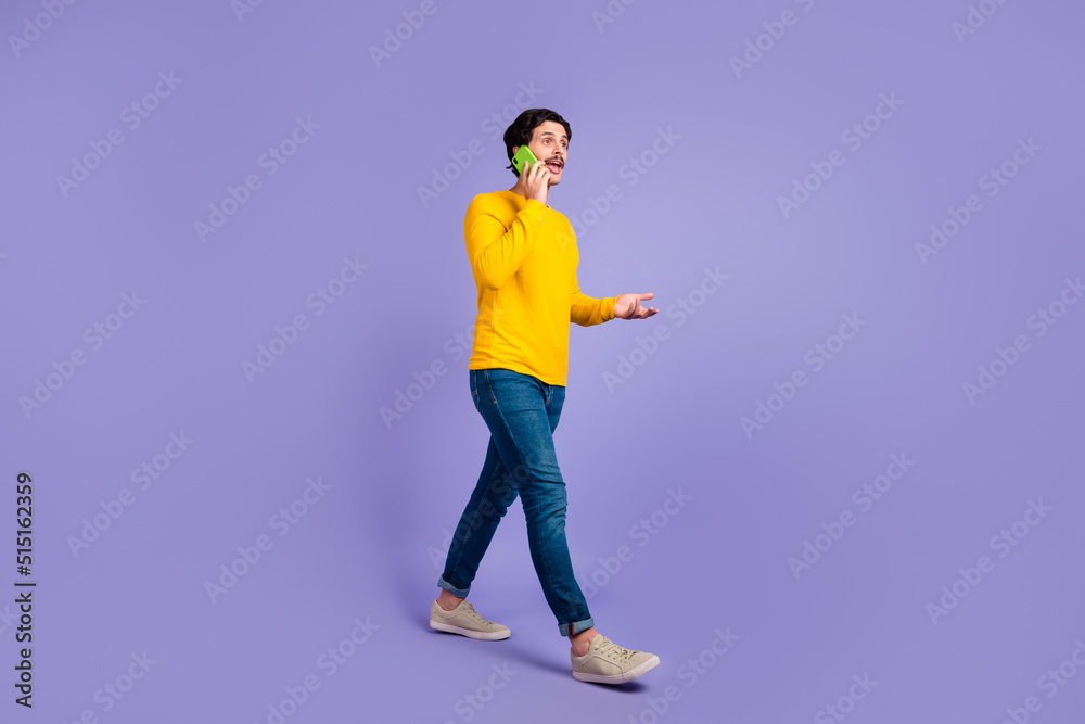 Full size portrait of positive person speak communicate telephone walking isolated on purple color background