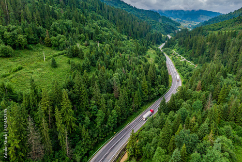 red cargo truck on the higthway. cargo delivery driving on asphalt road through the mountains. seen from the air. Aerial view landscape. drone photography.