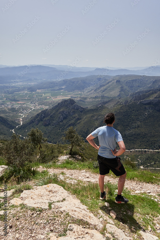 vertical shot of hiker with ponytail looking at view from top of Monduver mountain
