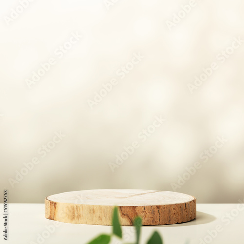 Wood slice podium with eucalyptus leaves on beige background for cosmetic product mockup