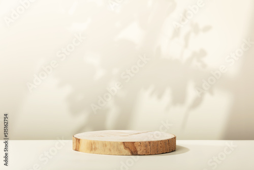 Fototapeta Naklejka Na Ścianę i Meble -  Wood slice podium with leaves  and window shadows on beige background for cosmetic product mockup
