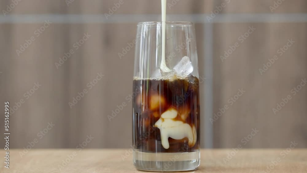 Pouring of sweet condensed milk into black coffee; Vietnamese iced coffee