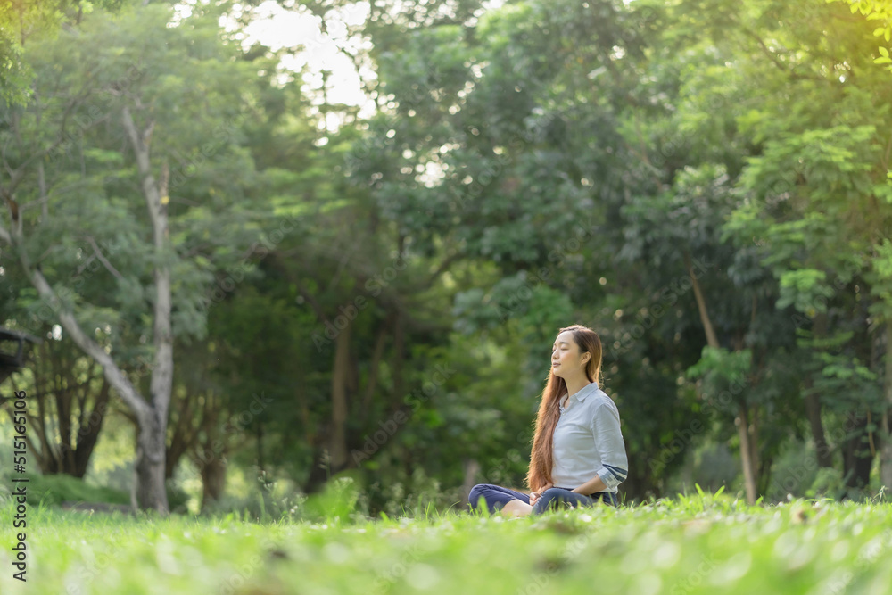 Happy woman doing meditation and relaxing in the park. Meditation in nature. Concept of healthy lifestyle and relaxation. Pretty woman practicing meditation on the grass Happy woman doing meditation and relaxing in the park. Meditation in nature. Concept of healthy lifestyle and relaxation. Pretty woman practicing meditation on the grass