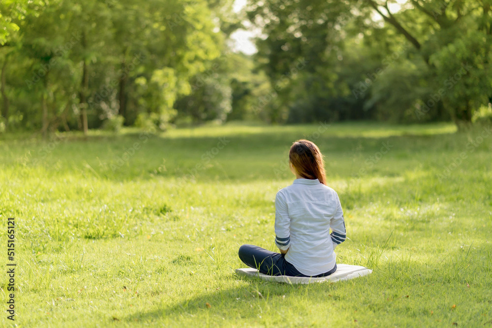 Back of asia woman practicing meditation in the park. Throght happiness from inner peace. Back of asia woman practicing meditation in the park. Throght happiness from inner peace.