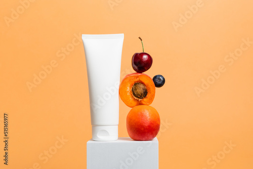 Fototapeta Naklejka Na Ścianę i Meble -  Facial cream or mask bottle mockup with fresh fruits on cube podium, nourishing skincare