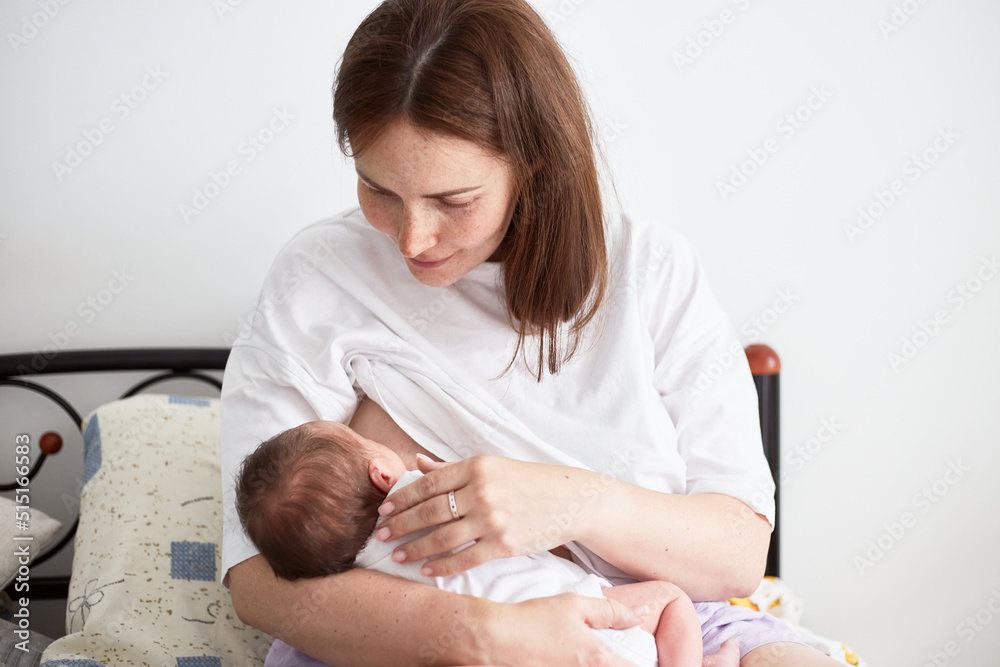 Mother breastfeeding her newborn baby boy. Realistic home portrait