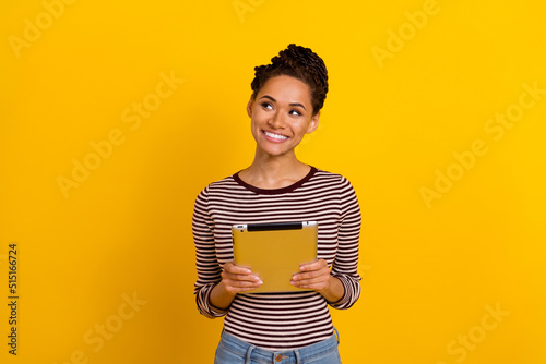 Photo of cheerful charming lady hands hold tablet look interested empty space isolated on yellow color background