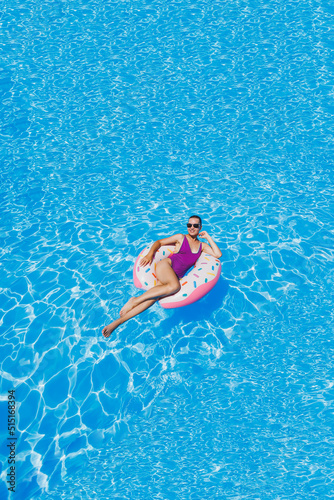 Slim woman in sunglasses in the pool in an inflatable swimming ring in a bright swimsuit, summer photo, swimming photography, summer woman photos. Beach fashion