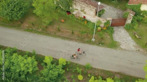 Young adult man and woman riding a bicycle together outdoor  in countryside natural park. Two person or couple in love in the nature, healthy lifestyle. Aerial shot, drone camera point of view.