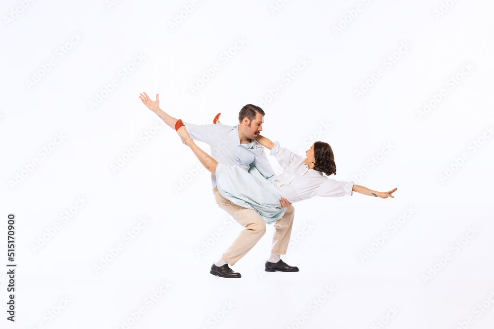 Portrait of young beautiful couple, man and woman, dancing twist isolated over white studio background