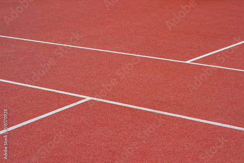 Close up on a white line in artificial red turf, on a street basketball, handball, volleyball, futsal, rugby, hockey and football field, in a sports background