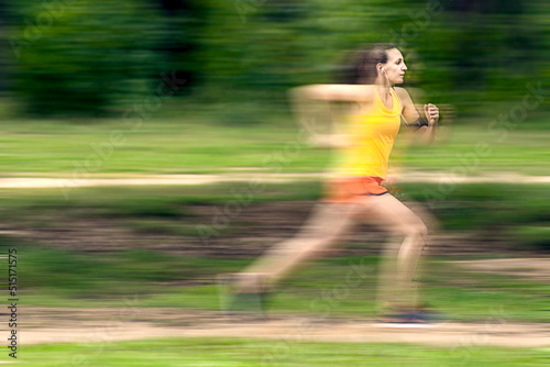 Young female sprinter running at speed. Motion blurred background