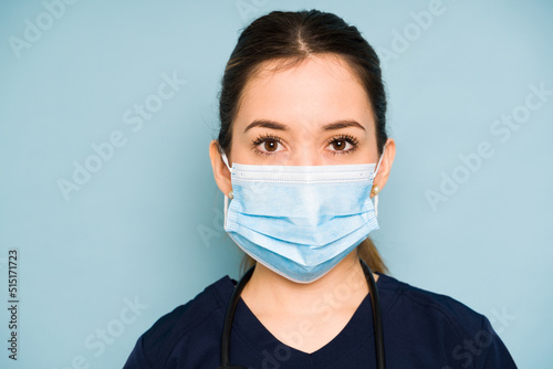 Closeup of a woman working in health care wearing scrubs and a face mask in a studio