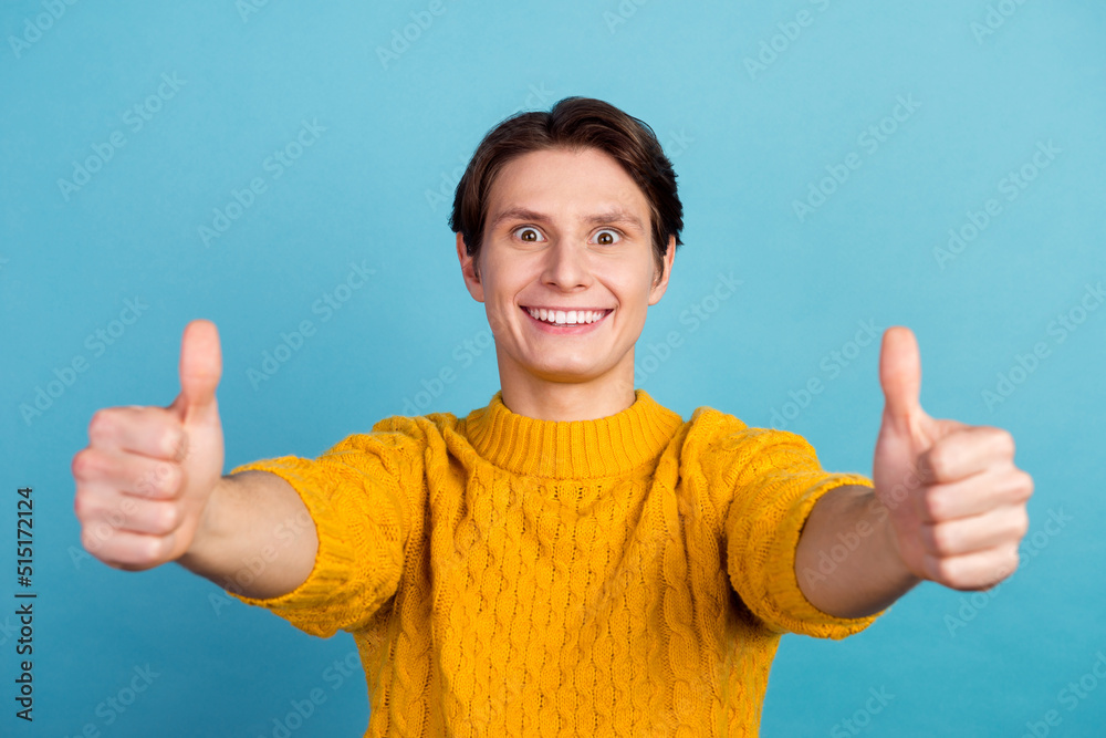 Portrait of man in basic clothing smiling showing thumbs up at camera isolated over blue color background Portrait of man in basic clothing smiling showing thumbs up at camera isolated over blue color background