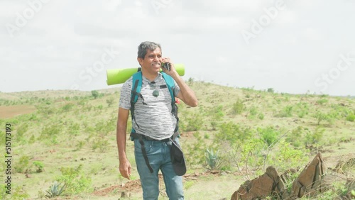 excited Happy middle aged man talking on mobile phone call during trekking on top of hill - concept of connection, technology and communication. photo