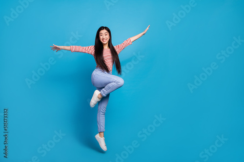 Fototapeta Naklejka Na Ścianę i Meble -  Full length photo of pretty charming lady dressed red shirt jumping high arms sides empty space isolated blue color background