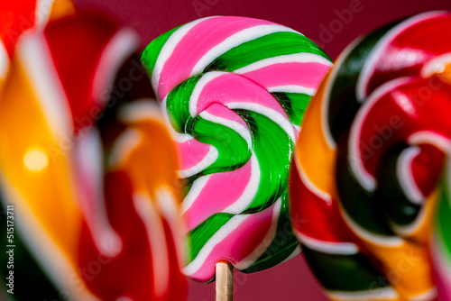 Round twisted pink green caramel lollipops on pink background. Colored assorted of sweet candies with fruit flavor. Sugar dessert for children's birthday. Handmade sweets for holiday. Close up.