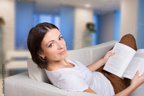 Young -woman drinking tea while reading book on sofa at home