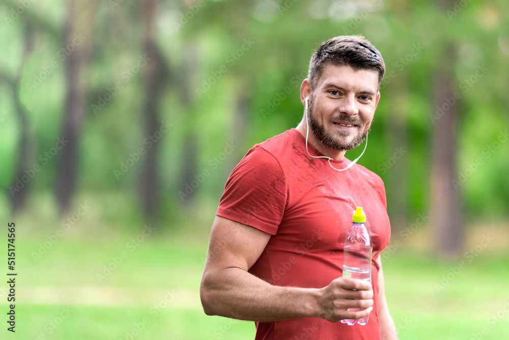 Happy fitness man with a bottle of water while jogging in the park. Healthy, fitness, wellness lifestyle. Sport, cardio, workout concept Happy fitness man with a bottle of water while jogging in the park. Healthy, fitness, wellness lifestyle. Sport, cardio, workout concept
